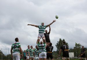 En grönvit spelare är högt upp i luften och tar bollen framför motståndaren.